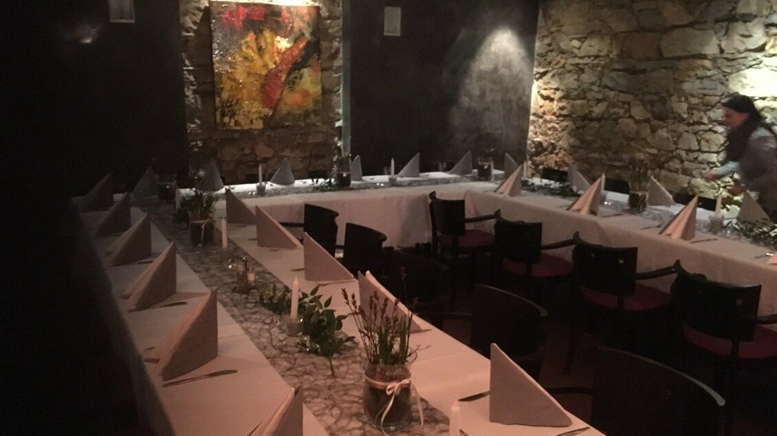 Ein ansprechend dekorierter Innenraum eines Restaurants mit Steinen und Tischen, die für Gäste vorbereitet sind. An der Wand hängt ein buntes Gemälde. | © Markus Nussbacher