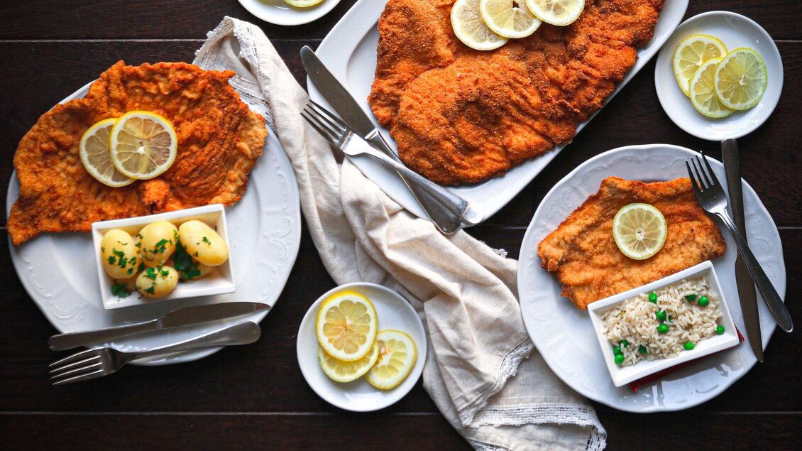 Ein köstliches Gericht mit frittiertem Fisch, garniert mit Zitronenscheiben. Dazu gibt es Kartoffeln und eine Beilage in einer Schüssel. | © 3 Goldene Kugeln