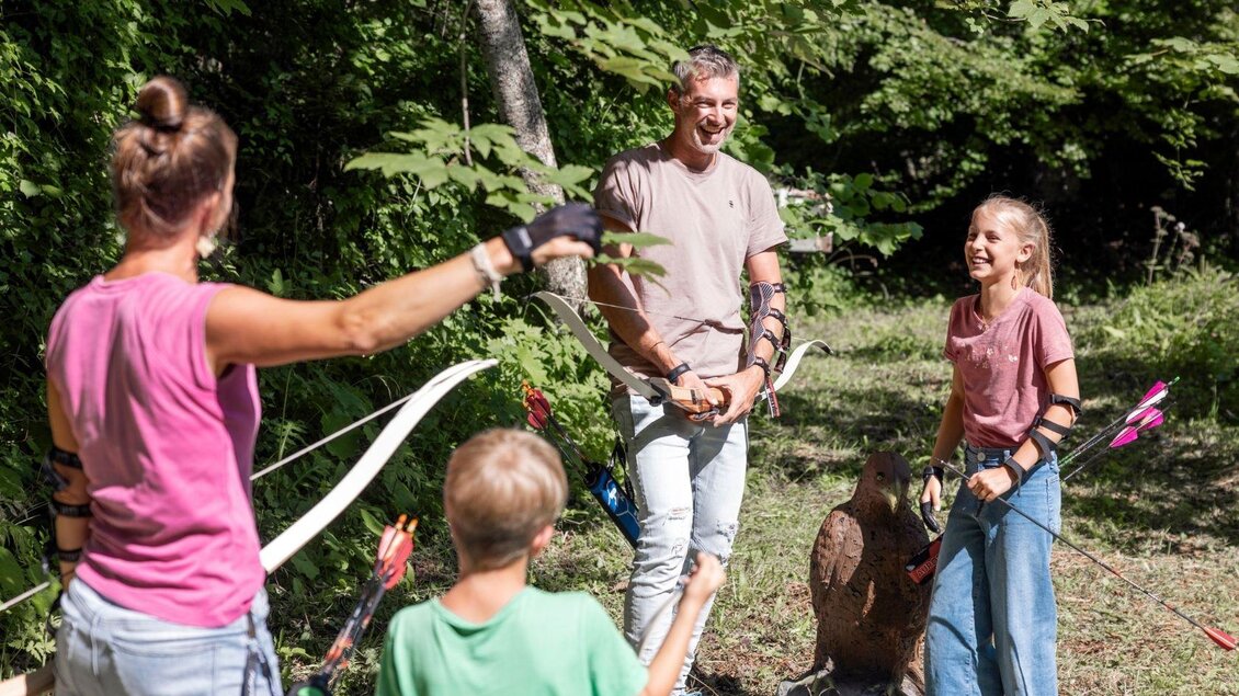 Eine Familie hat Spaß beim Bogenschießen in der Natur. Sie lachen und genießen die Zeit miteinander. | © www.zloam.at