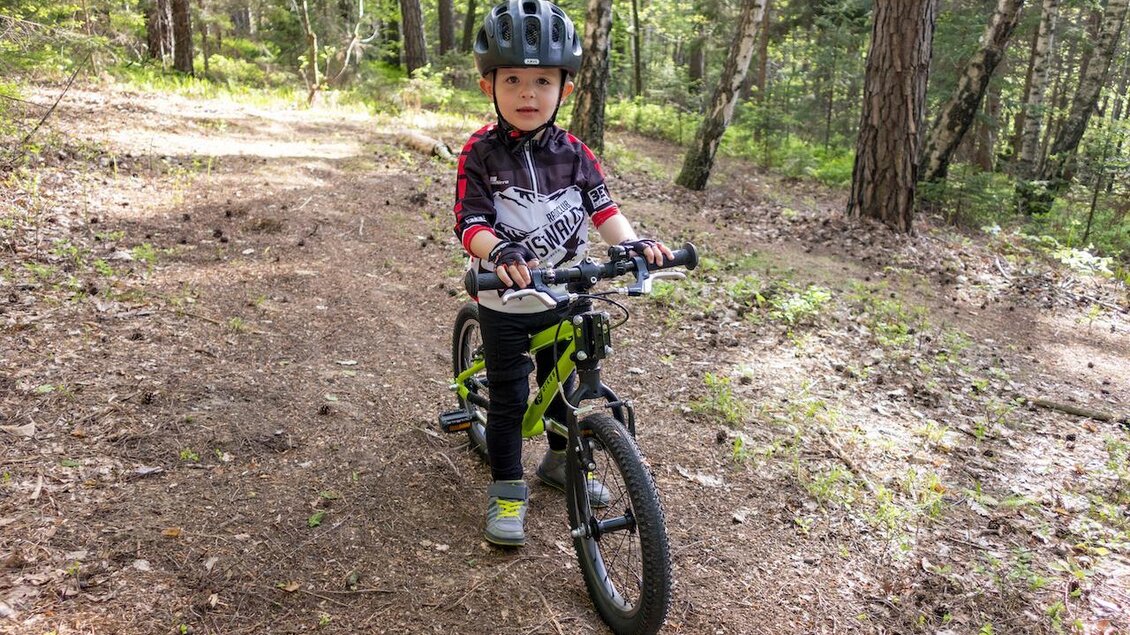 Ein kleiner Junge fährt auf einem Fahrrad auf einem Waldweg. Er trägt einen Helm und sportliche Kleidung. | © 3Eiben Kids Bike Park