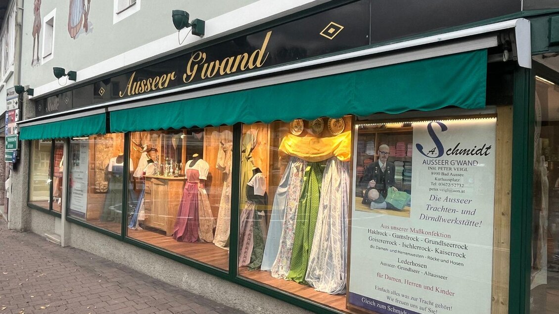 Ein Geschäft mit dem Namen "Ausseer Grand", das traditionelle Trachtenkleidung verkauft. Die Schaufenster sind mit bunten Kleidern dekoriert. | © TVB Ausseerland-Salzkammergut_Nathalie Schröttenhamer
