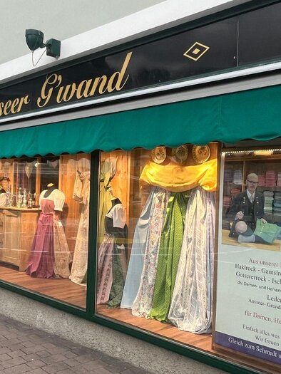 A store named "Ausseer Grand" that sells traditional folk costumes. The display windows are decorated with colorful dresses. | © TVB Ausseerland-Salzkammergut_Nathalie Schröttenhamer
