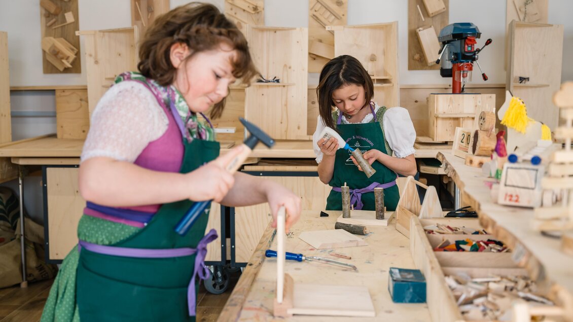 Zwei Kinder arbeiten in einer Werkstatt. Sie benutzen Werkzeuge, um Holzprojekte zu erstellen.