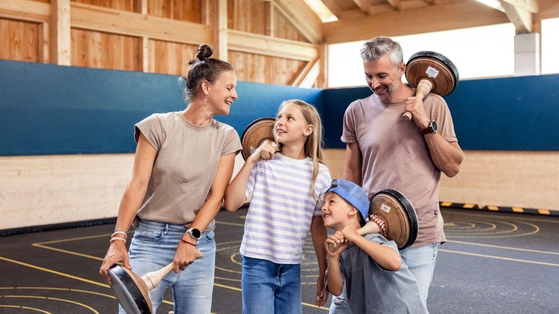 Eine Familie trainiert zusammen mit Gewichten in einer Sporthalle. Sie lachen und haben Spaß beim gemeinsamen Sport. | © www.zloam.at