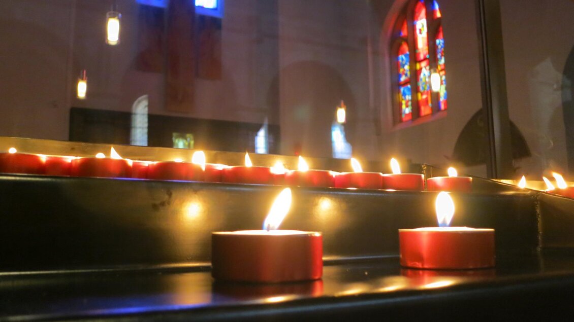 Rote Teelichter brennen vor bunten Glasfenstern in einer Kirche. Der Raum hat eine ruhige, meditative Atmosphäre. | © Abtei Seckau