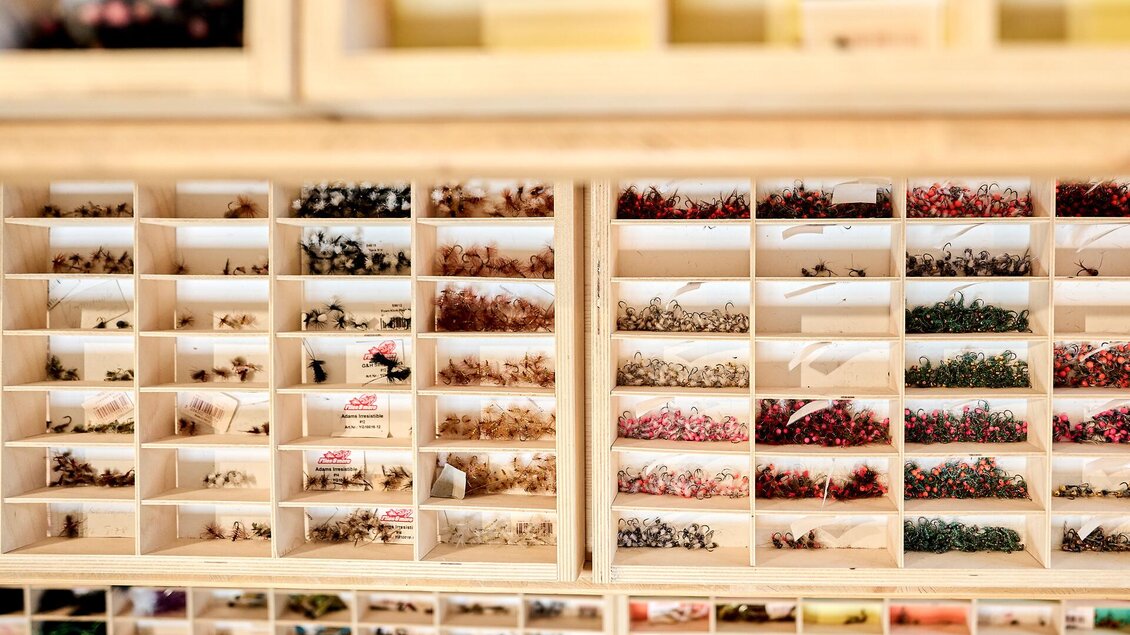 Eine Holzkommode mit zahlreichen kleinen Fächern, die verschiedene dekorative Elemente enthalten. Die Farben und Formen sind vielfältig und gut sortiert.