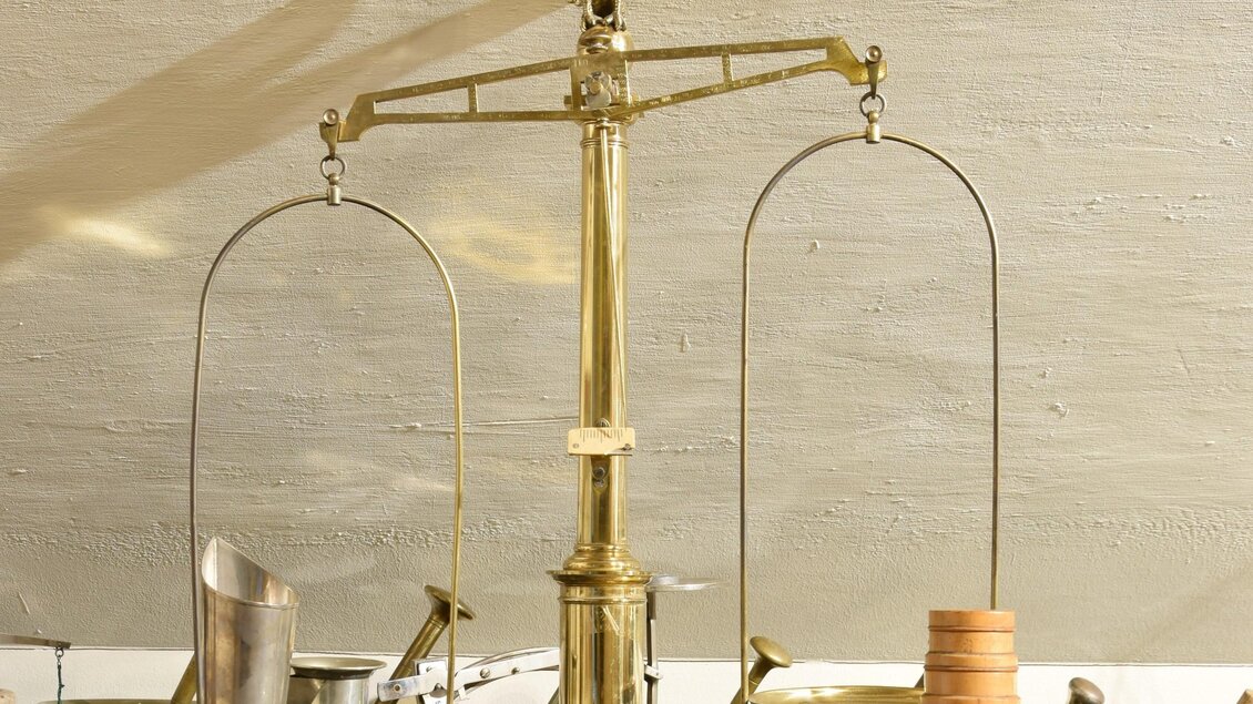 Alte goldene Balkenwaage mit Adlerfigur und Messgefäßen im Adler Apotheken Museum Graz | © Adler Apotheken Museum