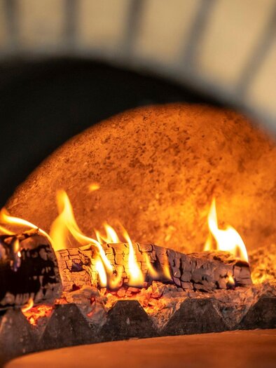 Ein gemütlicher Holzofen mit loderndem Feuer. Die warmen Flammen strahlen eine einladende Atmosphäre aus. | © TV Region Graz - Lunghammer
