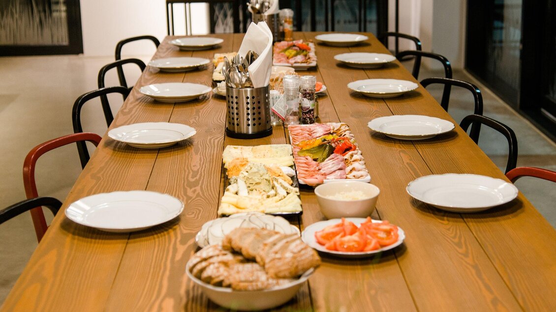 Ein großer Tisch mit leeren Tellern und verschiedenen Gerichten. Die Atmosphäre ist einladend und bereit für ein gemeinsames Essen. | © Region Graz