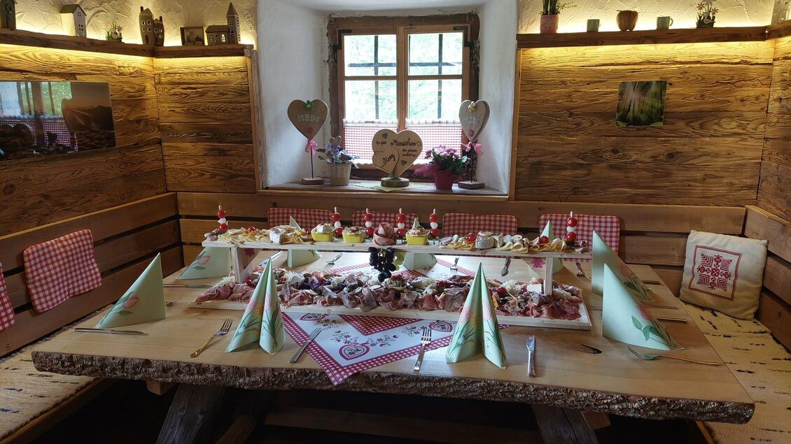 Ein gemütlicher Raum mit einem großen Holztisch, der für eine festliche Feier eingedeckt ist. Auf dem Tisch stehen verschiedene Leckereien und dekorative Elemente. | © Erwin Troger