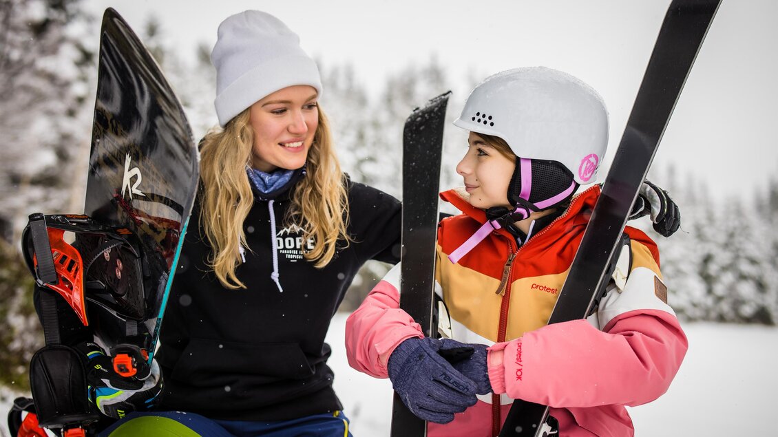 Zwei Skifahrerinnen stehen auf einem verschneiten Berg. Die eine gibt der anderen Tipps und beide sind in Winterkleidung. | © Gasthof Albmlick