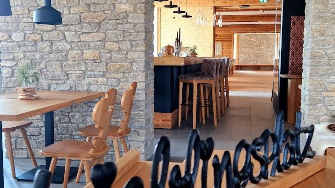 Ein stilvolles Restaurantinterieur mit Holz- und Steinakzenten. Auf einem Tisch steht eine dekorative Beschriftung "Lieblingsplatz". | © Almerwirt