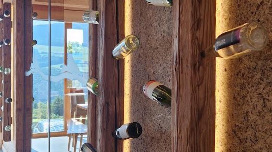 Ein moderner Weinkeller mit Holzregalen, die Flaschen attraktiv präsentieren. Die Beleuchtung sorgt für eine gemütliche Atmosphäre. | © Almerwirt