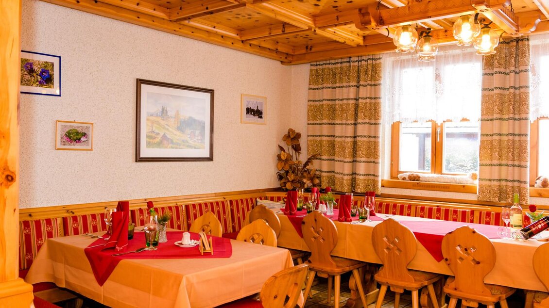 Ein gemütliches Restaurant mit Holzmöbeln und quadratischen Tischen. Die Tische sind schön gedeckt und es gibt sanfte Lichtquellen. | © Almidylle Sabathy