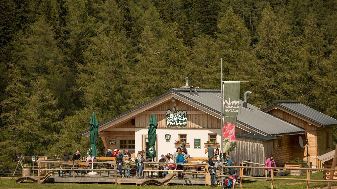 Eine gemütliche Berghütte mit vielen Gästen im Freien. Umgeben von dichten Wäldern und einer schönen Landschaft. | © Klaus Morgenstern