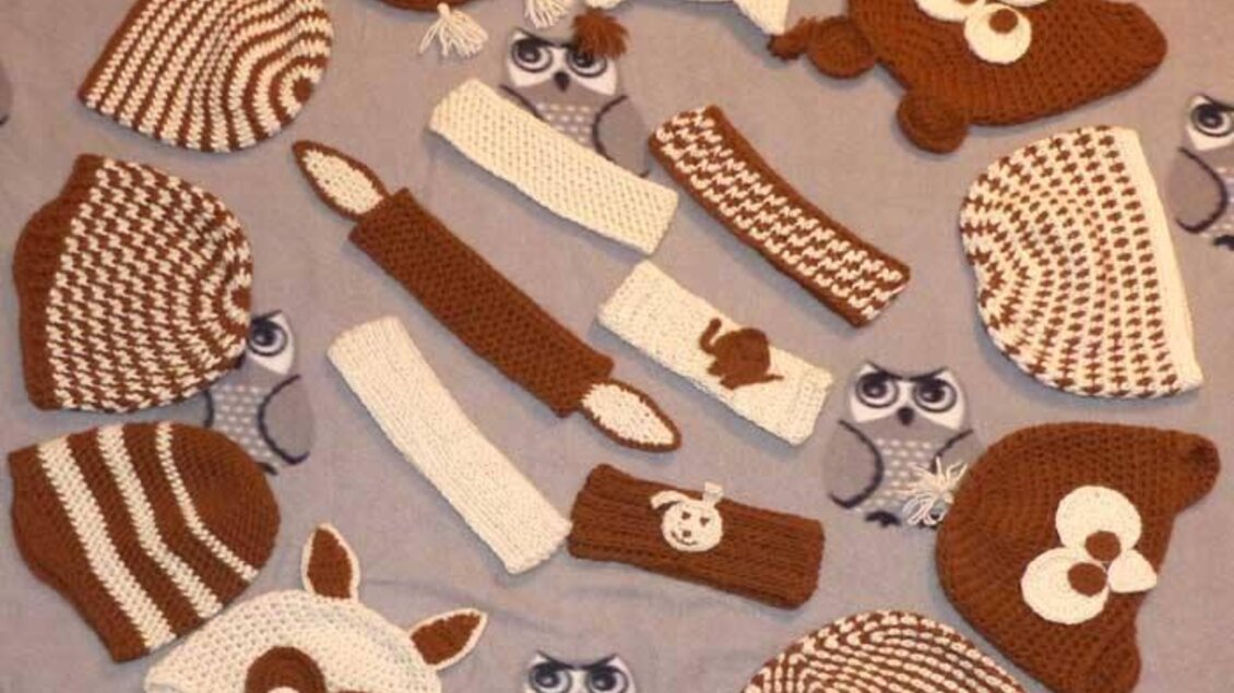 Eine Vielzahl von handgefertigten, gehäkelten Mützen in braunen und weißen Farbtönen. Die Mützen haben verschiedene Designs, darunter Tiermotive wie Eulen und Bären. | © Alpakas Bratschitz