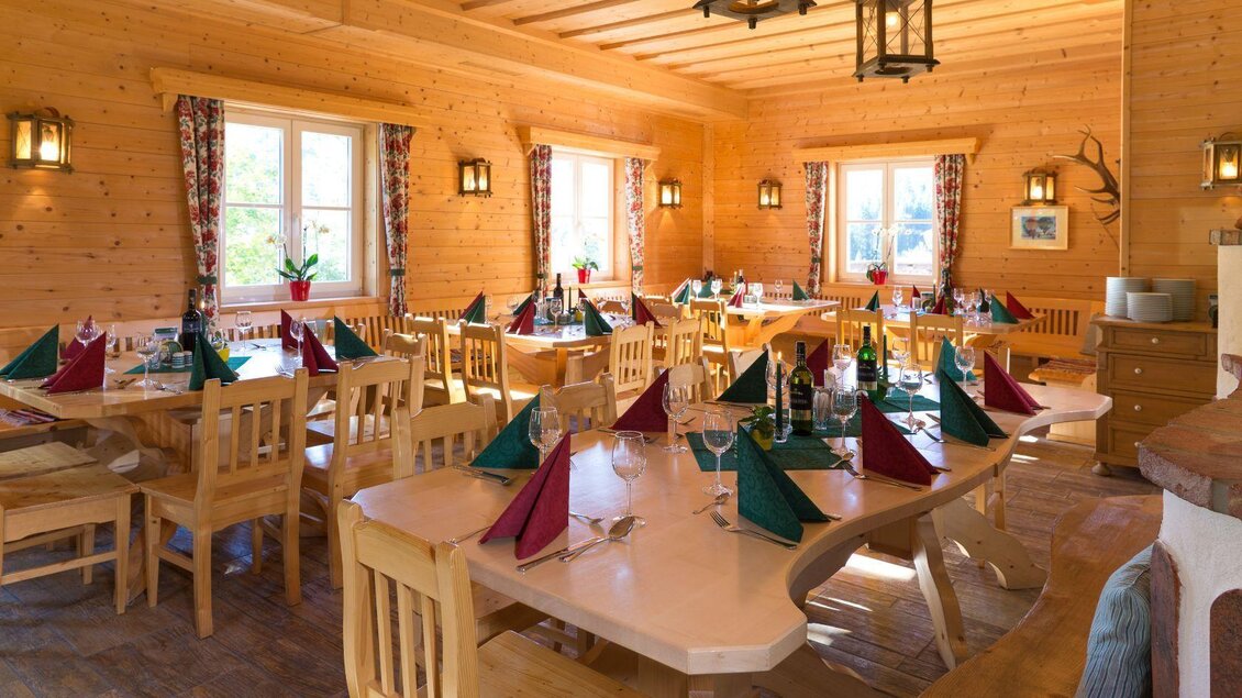 Ein einladendes Restaurant mit Holzdekor und warmem Licht. Die Tische sind elegant gedeckt mit bunten Servietten. | © Gerhard Wolkersdorfer