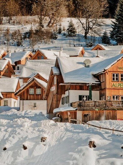 A picturesque winter landscape with snow-covered cottages. In the foreground stands a charming wooden building named "Alpenstüble." | © Alpenstubn