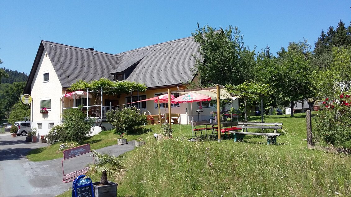 Ein charmantes Haus mit Terrasse und Sonnenschirmen. Umgeben von Grün und Bäumen, bietet es einen einladenden Außenbereich. | © Gregorhansl