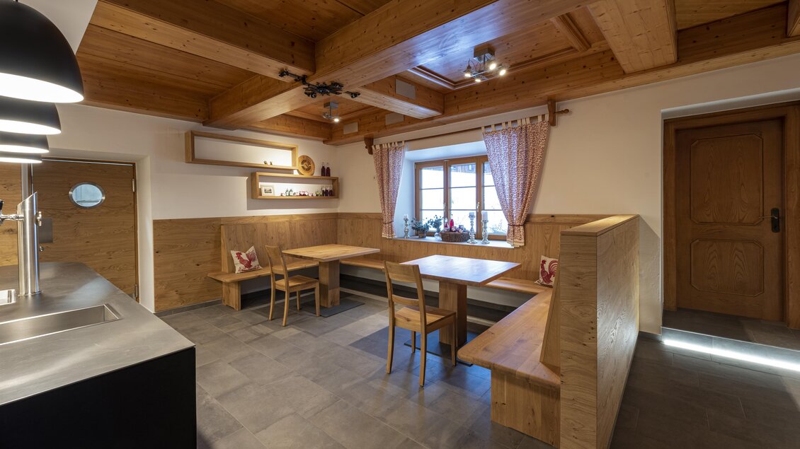 Eine moderne Küche mit Holzverkleidung und einem offenen Essbereich. Helle Fenster sorgen für eine freundliche Atmosphäre. | © Mareike Claar