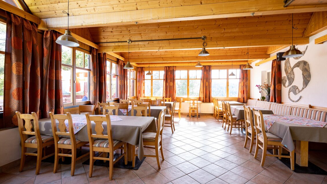 Ein einladender Raum mit Holztischen und Stühlen. Große Fenster lassen viel Licht herein und schaffen eine angenehme Atmosphäre. | © TV Region Graz-Harry Schiffer