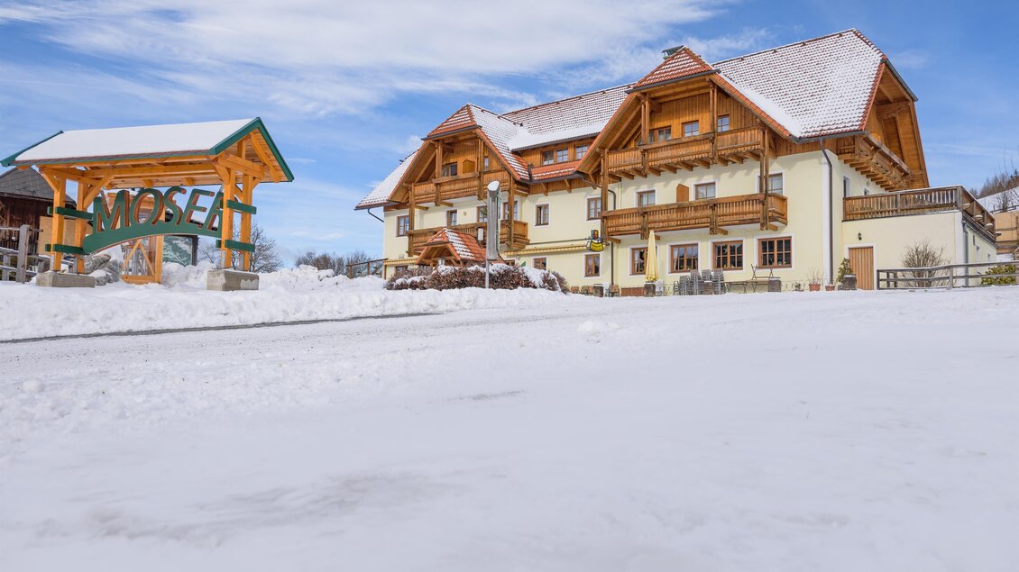 Ein charmantes Haus im Schnee mit traditioneller Architektur und einem einladenden Eingangsschild. Die ruhige Winterlandschaft bietet eine malerische Kulisse. | © Alpengasthof Moser