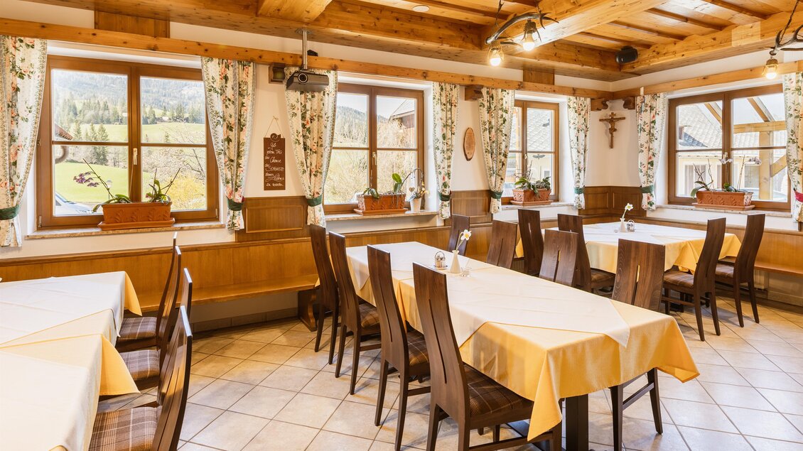 Ein gemütliches Restaurant mit Holzmöbeln und sinnvollen Tischdecken. Große Fenster bieten einen Blick auf die umliegende Landschaft.