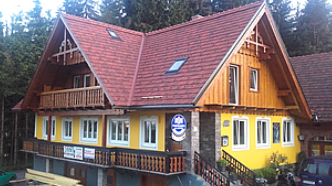 Ein gemütliches Haus mit einem roten Dach und gelber Fassade. Umgeben von Bäumen, vermittelt es ein einladendes Ambiente. | © Alpengasthof Strutz