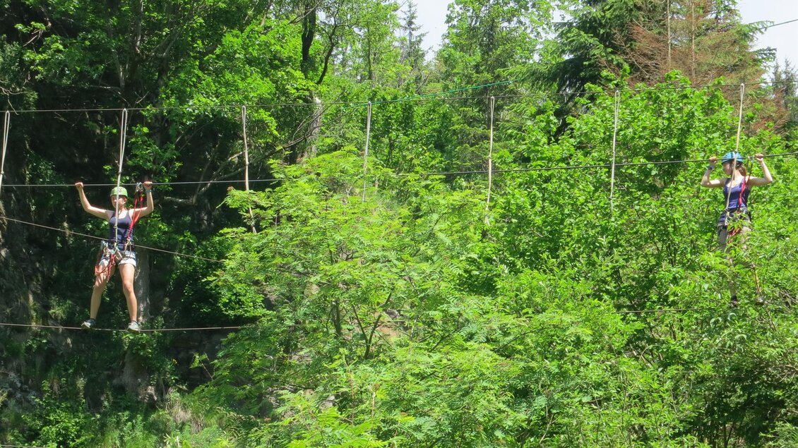 Zwei Personen balancieren auf einem Seilpfad zwischen Bäumen. Die Umgebung ist grün und üppig. | © Manuela Machner