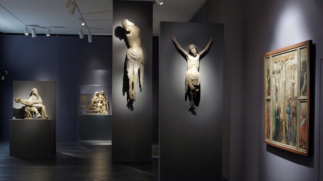 Ein moderner Ausstellungsraum mit Skulpturen und einem Gemälde in der Alten Galerie. Die Beleuchtung hebt die Kunstwerke hervor und schafft eine mystische Atmosphäre. | © UMJ