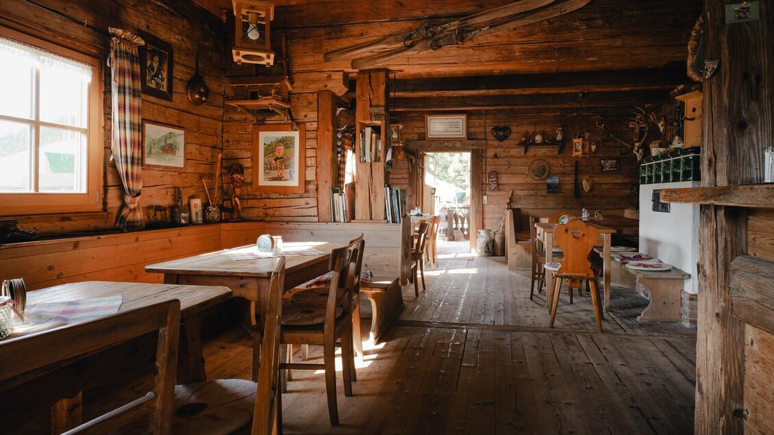 Ein gemütliches Holzhaus mit rustikaler Inneneinrichtung. Es gibt Tische, Stühle und eine warme, einladende Atmosphäre.