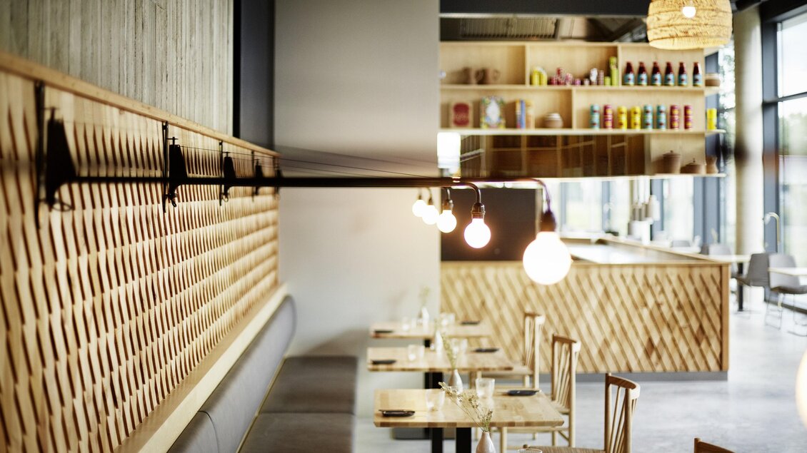 Ein modernes Restaurant mit Holzakzenten und gedämpfter Beleuchtung. Die Tische sind schön gedeckt und die Wandgestaltung ist stilvoll. | © Arravané - Gerhard Wasserbauer