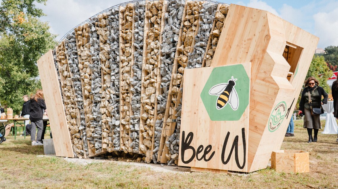 Ein innovativer Bienenhaus aus Holz und Steinen, gestaltet als Skulptur. Die Struktur bietet Lebensraum für Bienen und steht in einer grünen Umgebung. | © Bee Wild