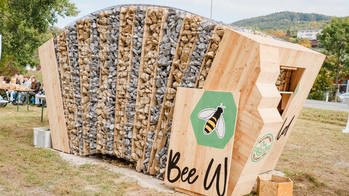 Ein innovatives Bienenhaus aus Holz und Steinen, das umweltfreundliches Design zeigt. Es ist Teil eines Projekts zur Förderung von Bienen und Biodiversität. | © MotionAds