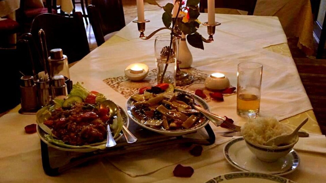 Ein romantisch gedeckter Tisch mit Kerzenlicht und rosern. Auf dem Tisch befinden sich verschiedene Gerichte und Reis. | © Asia Restaurant
