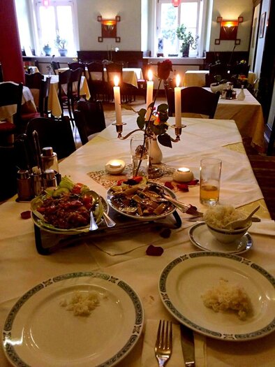 A romantically set table with candlelight and roses. On the table, there are various dishes and rice. | © Asia Restaurant