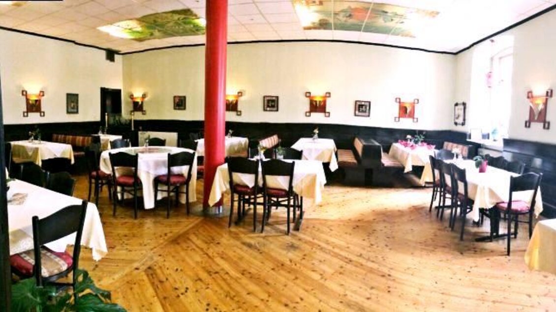 Ein stilvolles Restaurant mit Tischen und Stühlen, dekoriert mit Blumen und Kunstwerken an den Wänden. Der Holzboden und die sanfte Beleuchtung schaffen eine gemütliche Atmosphäre. | © Asia Restaurant