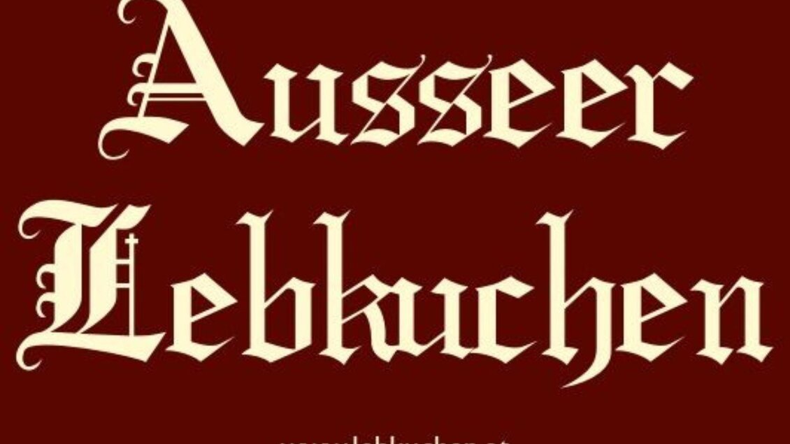 Ein rotes Schild mit der Aufschrift „Ausseer Lebkuchen“ in dekorativer Schrift. Darunter befindet sich die Website „www.lebkuchen.at“.