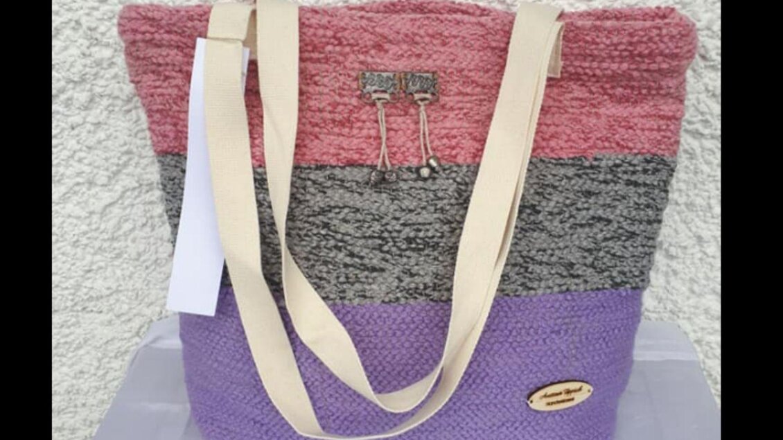 Eine farbenfrohe Tasche mit einem modernen Streifenmuster in Rosa, Grau und Lila. Die Tasche hat eine praktische Form und schlichte Tragegurte. | © Ausseer Teppich_Melanie Schlömmicher