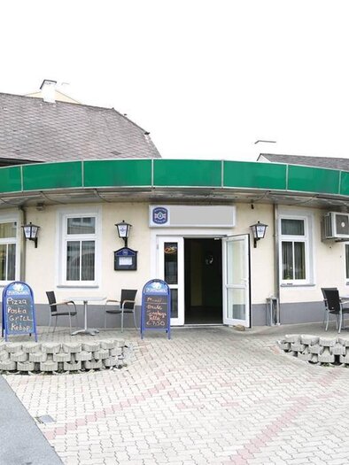 Ein rundes Gebäude mit grünem Dach und Tischen im Freien. Es befindet sich an einer Straßenecke in einer ruhigen Umgebung. | © keine Kenntnis