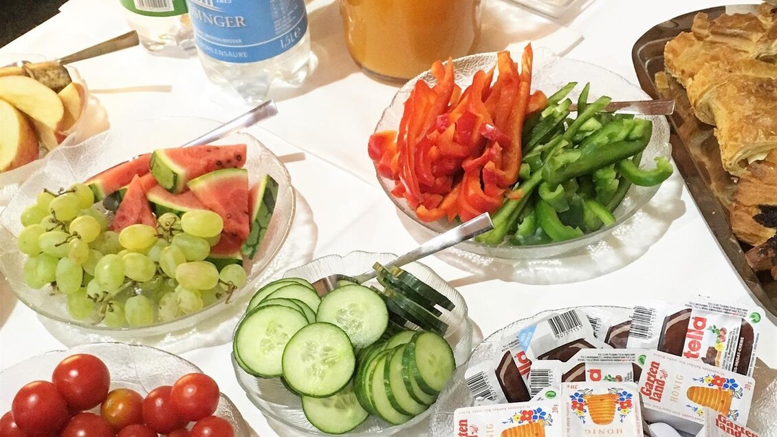 Ein reichhaltiges Buffet mit frischen Früchten, Gemüse und verschiedenen Beilagen. Dazu sind Getränke wie Wasser und Fruchtsäfte angeordnet. | © Bäckerei & Konditorei Wolf