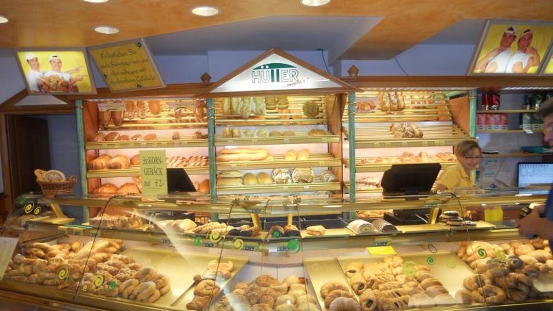 Eine gemütliche Bäckerei mit einer Vielzahl von frisch gebackenem Brot und Gebäck. Im Hintergrund ist eine freundliche Verkäuferin zu sehen. | © Bäckerei Konditorei Café Hütter