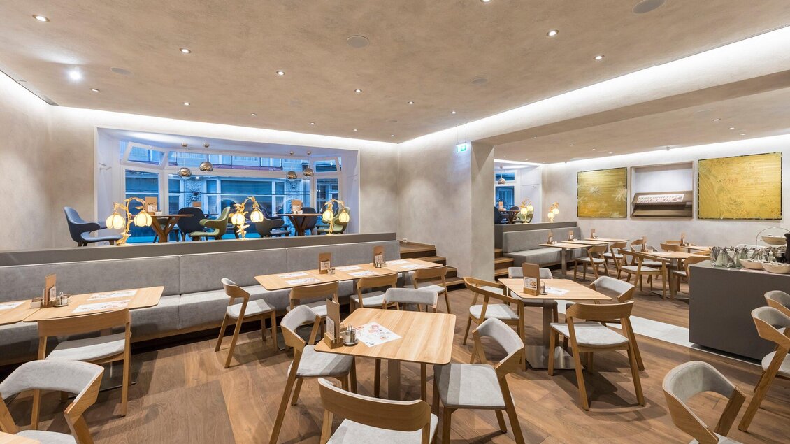 Ein modernes Restaurant mit elegantem Design und warmem Licht. Es gibt Holzstühle und Tische sowie gemütliche Sitzbereiche. | © Sorger - Werner Krug