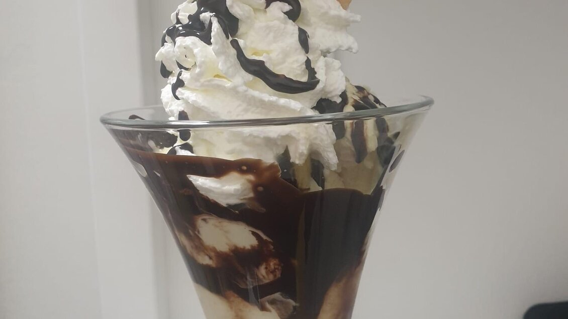 Ein köstliches Eisbecher mit Schokolade, Sahne und einer Waffel. Oben ist eine Kirsche dekoriert. | © Tourismusverband Oststeiermark