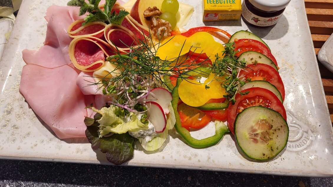 Ein Teller mit verschiedenen Aufschnittsorten, frischem Gemüse und einer kleinen Butter- und Marmeladensorte. Der Anblick wirkt appetitlich und einladend. | © Tourismusverband Oststeiermark