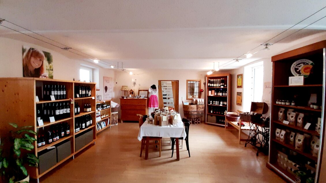 Ein einladendes Geschäft mit Regalen voller Wein und regionaler Produkte. In der Mitte steht ein Tisch, und eine Person schaut sich die Waren an. | © Bäcksteffl Bauernspezereien