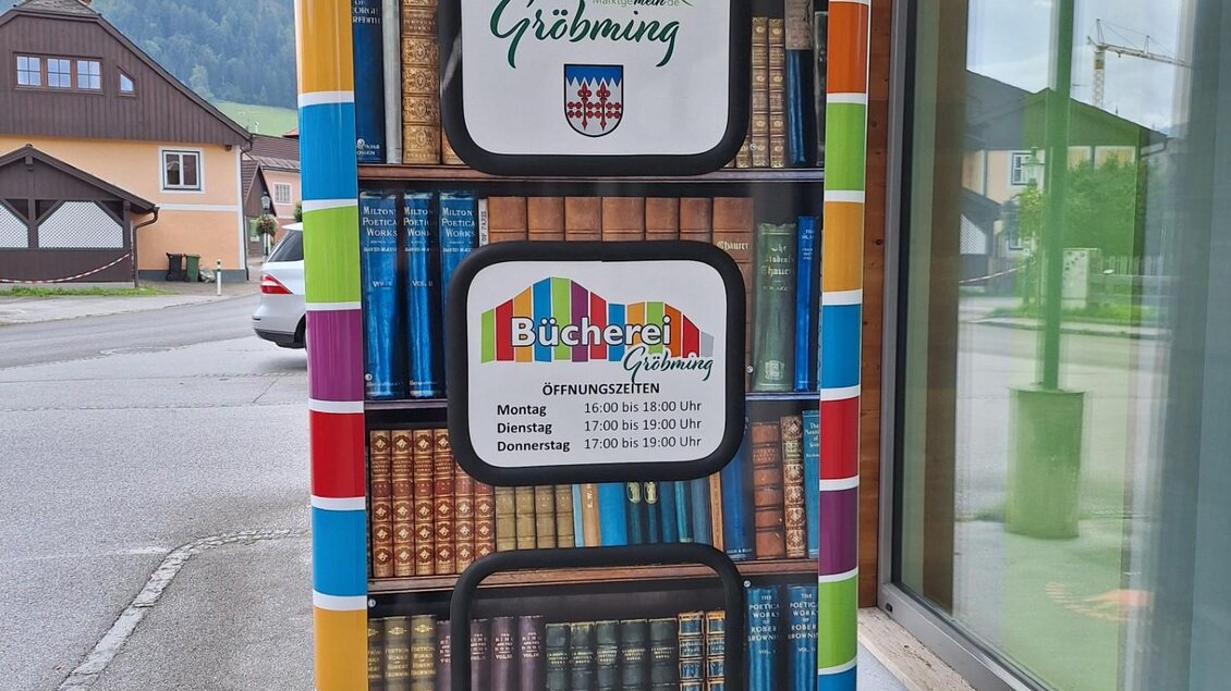 Eine kreative Bücherbox mit bunten Regalen, die wie ein Bücherstapel aussieht. Sie befindet sich in der Stadt Gröbming und lädt zum Lesen ein. | © Bücherei Gröbming 