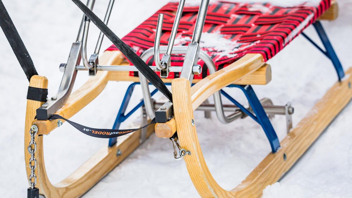Ein Schlitten mit einem roten Gitter und Holzrahmen steht auf Schnee. Er eignet sich perfekt für winterliche Abenteuer im Freien. | © Tourismusverband Murau