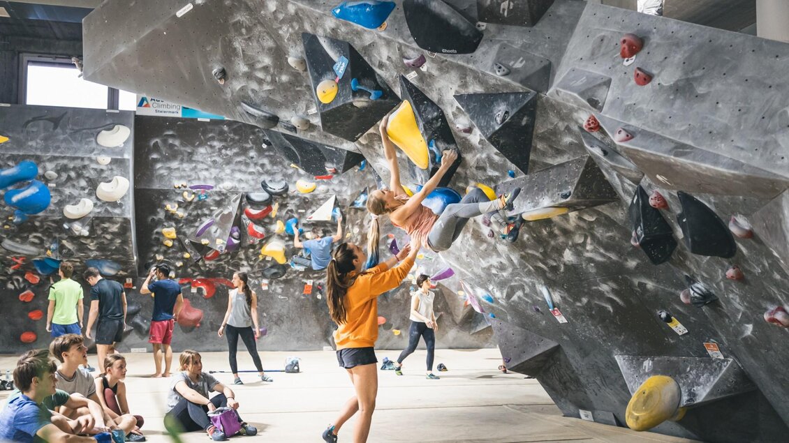 Menschen beim Bouldern an künstlichen Kletterwänden im BLOC HOUSE Graz 