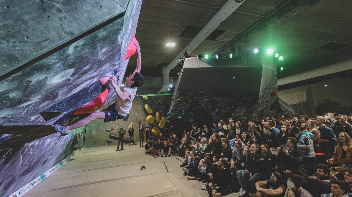Kletterer beim Wettkampf an Überhangwand, Publikum schaut im BLOC HOUSE Graz zu | © by AchimR